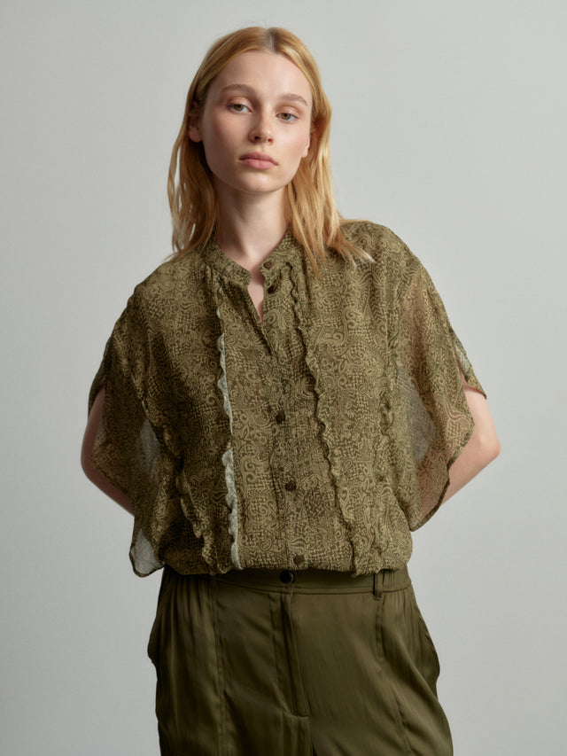 Blouse Benaja maze garden - Introducing Blouse Benaja, adorned with delicate frills and featuring airy,...
